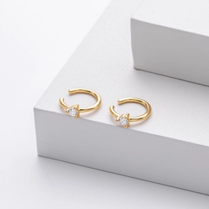 Detailed view of gold C-shaped ear cuffs with cubic zirconia on geometric stands