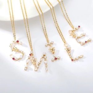 Detail of five gold necklaces forming SMILE with crystals, pearls and red gemstones
