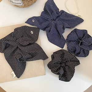 Detailed shot of retro polka dot scrunchie with handmade label and metal buckle