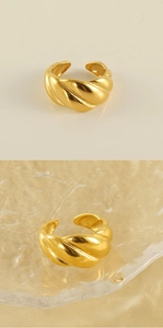 Detailed view of adjustable 18k gold croissant ring on textured glass and satin fabric