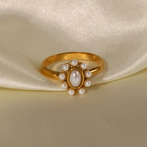 Detailed macro shot of vintage gold ring with white pearls on elegant beige silk fabric