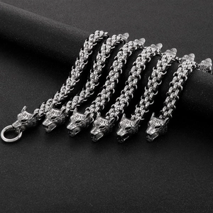 Braided leather wolf head bracelet with silver finish on textured black background