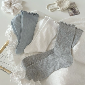 Three pairs of white and blue knit crew socks with lace trim ruffles on a clean background