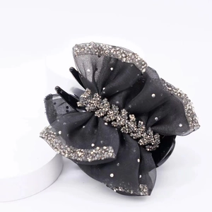 Détail de la pince à cheveux en organza noir élégant avec bordure en cristaux argentés