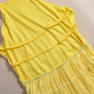 Detailed view of yellow dress with cross back straps and mesh lace patchwork fabric