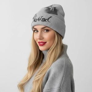 Detailed close-up of gray knit beanie featuring black Blessed embroidery and graphic print