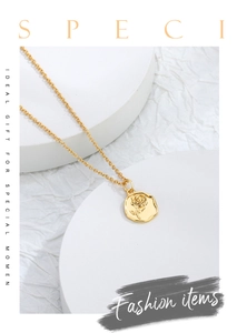 Detailed view of a gold rose embossed pendant on a minimalist white display