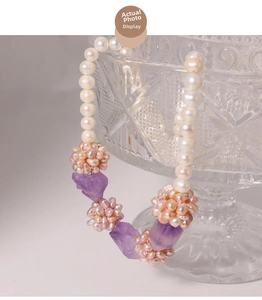 Detail of freshwater pearl necklace with amethyst clusters on a glass holder