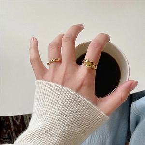 Close-up of vintage gold heart signet ring and minimalist wavy band on model hand