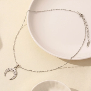 Detailed macro view of a silver crescent moon pendant necklace with delicate chain link