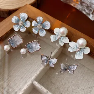 Set of four crystal flower and butterfly pearl stud earrings in a wooden jewelry box