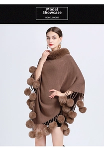 Detail of dark brown knitted poncho with faux fur collar and decorative pom-pom fringe