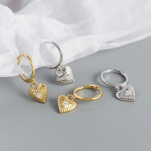 Detail of heart-shaped earrings in gold and silver finish with sparkling zircon stones