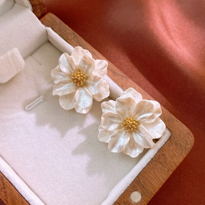 Macro view of floral earrings with pearlescent white petals and golden center detail