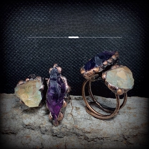 Detailed macro of irregular raw amethyst and green crystal rings on rustic bark texture