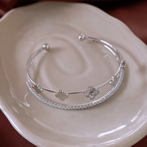 Macro view of double-layer open bangle with sparkling zircon clover and pavé diamonds