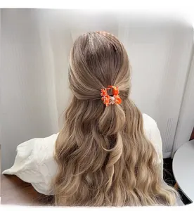Pince à cheveux marguerite en acétate ambré portée par une femme en intérieur doux