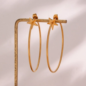 Close-up of gold oversized hoop earrings with star elements on a vintage metal stand