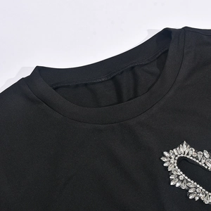 Détail de l'encolure d'un t-shirt noir ornée de strass brillants en forme de cœur