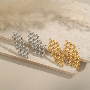 Détail de boucles d'oreilles chaîne tressée en or et argent sur fond de pierre naturelle