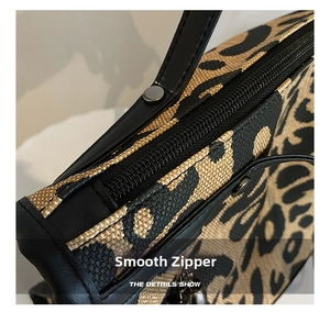 Close-up of leopard print fabric texture with smooth zipper and leather trim detail