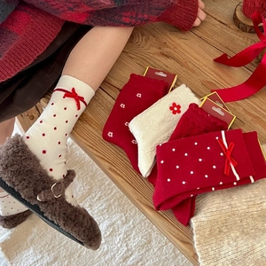 Close-up of thick festive Christmas socks with red bows and floral embroidery detail