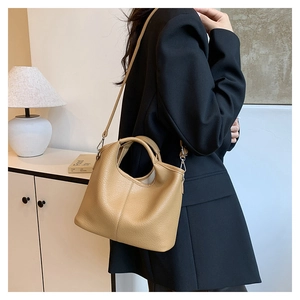 Detail view of khaki bucket bag showing the pebble grain leather texture on model
