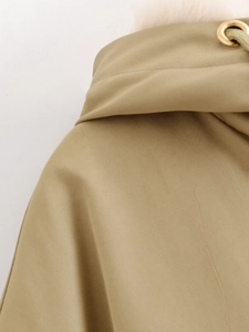 Detailed macro view of khaki woven fabric and gold metal eyelets on a parka coat hood