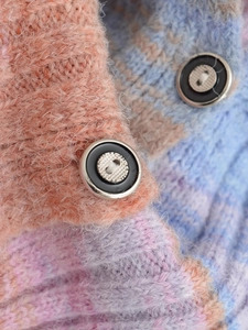 Close-up of multicolor gradient knit cardigan with fuzzy texture and metal-rimmed buttons