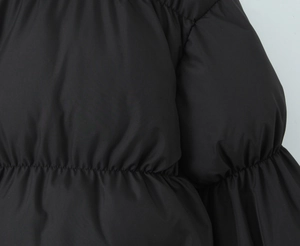 Detailed close-up of glossy black padded puffer jacket with elasticated stitching details