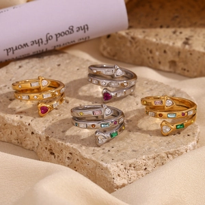 Macro view of multi-color heart and arrow zircon inlays on golden 18K layered rings
