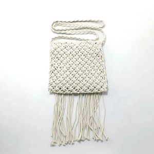 Detailed view of the woven diamond pattern and long fringe on the white macrame bag