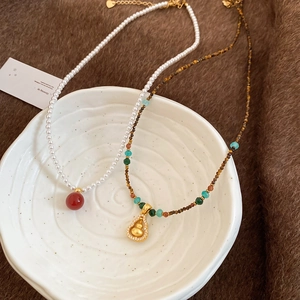 Detailed shot of ethnic gourd necklace with tiger eye stone and crystals on white ceramic