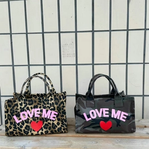 Canvas tote bags in leopard and camo print featuring pink LOVE ME text on a wooden bench