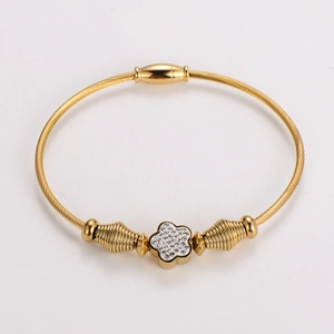 Close-up of golden cable wire bracelet featuring a crystal-studded floral charm decoration