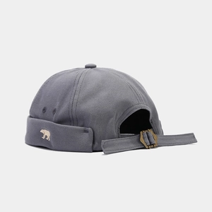 Close-up of bear embroidery and adjustable metal buckle on dark grey brimless miki hat