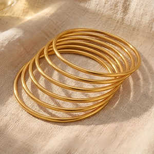 Close-up of 3mm gold stackable stainless steel bangles on beige textured fabric background