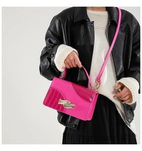 Chic magenta square handbag featuring crocodile texture and a wavy gold metal buckle