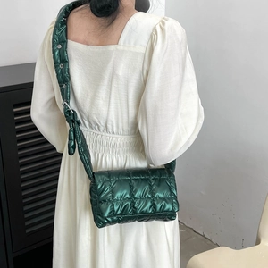 Detail of dark green quilted crossbody bag with matching wide shoulder strap on model