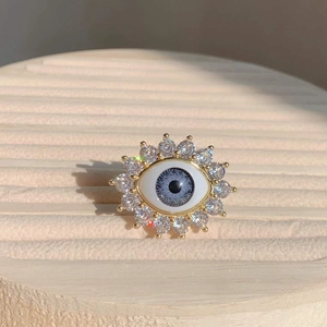 Macro detail of gold evil eye ring with blue resin iris and sparkling zircon pavé