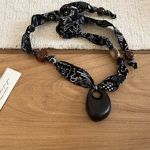 Detail of bohemian necklace with printed fabric, colorful resin beads and dark oval pendant