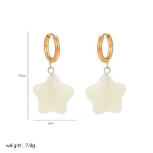 Detail shot of gold star drop earrings with size markers and white resin finish