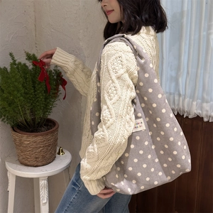 Detailed view of large grey polka dot tote bag with white spots and side fabric label