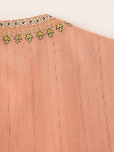 Detailed macro view of pink fabric featuring vertical stripes and intricate colorful embroidery
