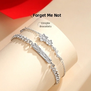 Detail of silver couple bracelets with forget-me-not flower charm and engraved bar design