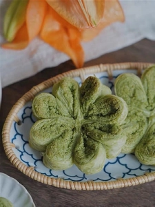 Close-up of Matcha pastry with flaky layers in a woven rattan snack basket with flowers