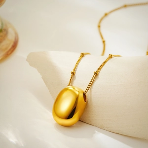 Minimalist 18K gold stainless steel necklace with pebble pendant on stone surface