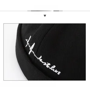 Detail of black docker hat with white hustle embroidery and premium knit texture