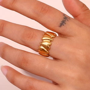 Close-up of golden irregular heart-shaped stainless steel ring worn on finger