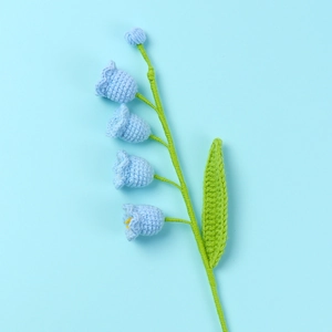 Macro detail of hand-knitted lily of the valley with blue yarn flowers and green stem